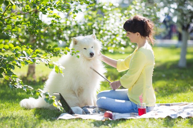 写真 公園で地面に座っている犬を持つ女性