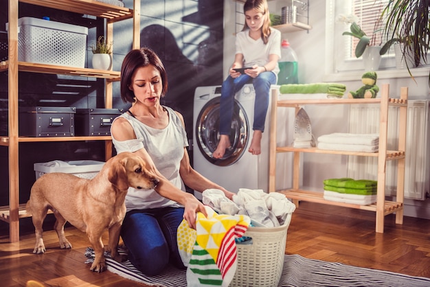 床に服を並べ替える犬を持つ女性