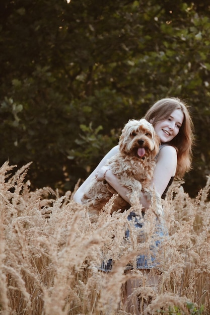植物の真ん中に立っている犬を持つ女性