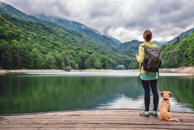 Donna con un cane in piedi sul molo sul lago