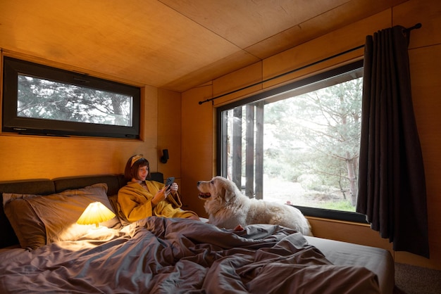 Woman with dog in tiny bedroom of a wooden house on nature