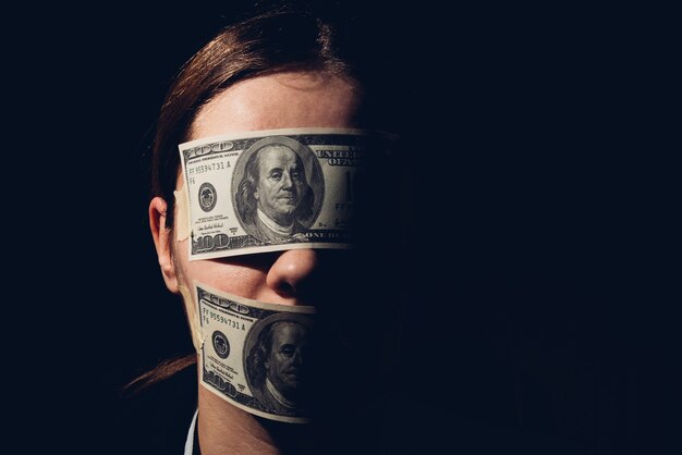 彼女の目を覆っているドル紙幣を持つ女性