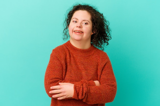 Woman with Down syndrome frowning face in displeasure, keeps arms folded.