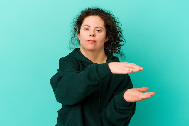 Foto donna con sindrome di down isolata tenendo qualcosa con entrambe le mani, presentazione del prodotto.