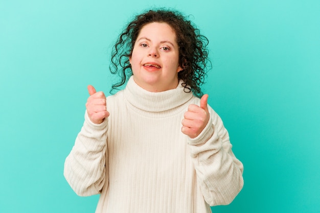 Woman with Down syndrome isolated raising both thumbs up, smiling and confident.