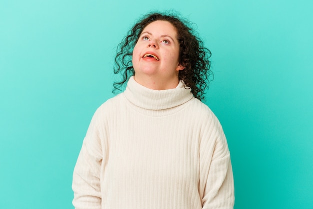 Woman with Down syndrome isolated relaxed and happy laughing, neck stretched showing teeth.