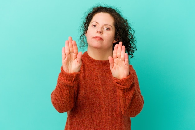 ダウン症の女性は、一時停止の標識を示している手を伸ばして立って孤立し、あなたを妨げています。