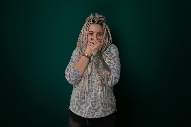 Woman with dreadlocks covering face with hands