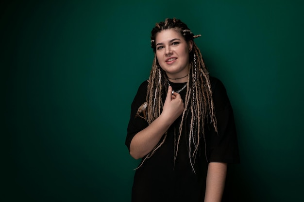 Woman with dreadlocks standing in front of green wall