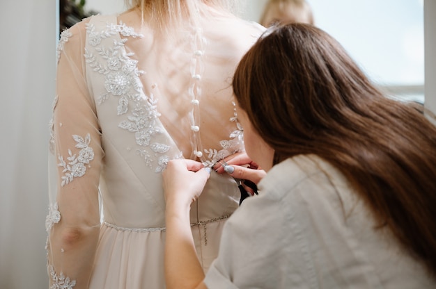 Woman with dressmaker  making final touch in bridal clothing shop