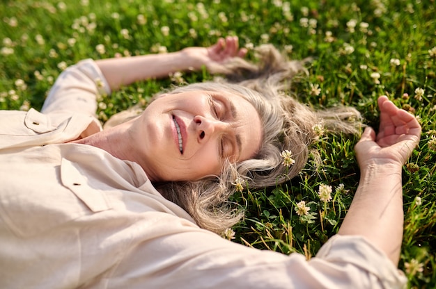 Woman with drooping eyelids lying on grass