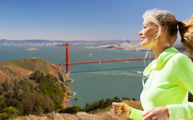 Photo woman with earphones running over san francisco