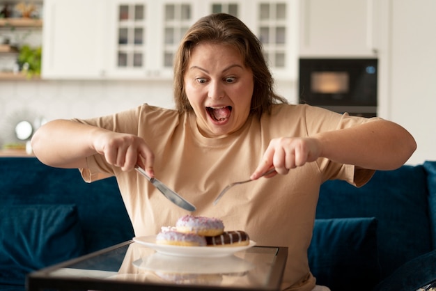 Foto donna con disturbi alimentari che prova a mangiare ciambelle