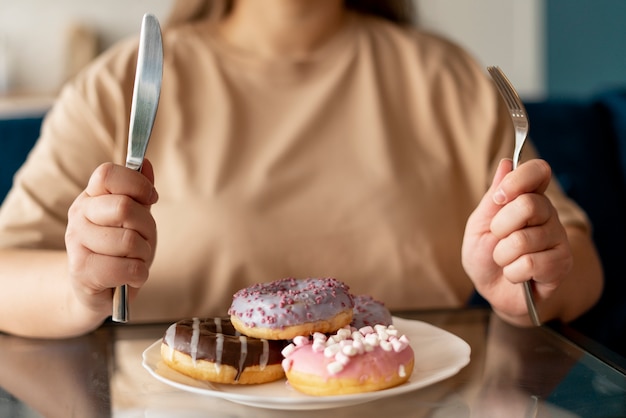 Photo woman with eating disorder trying to eat donuts