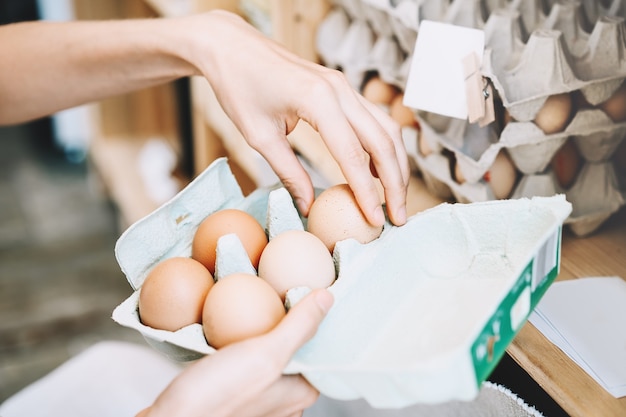 женщина с картонной коробкой для яиц покупает био органические яйца с местной фермы в магазине с нулевыми отходами