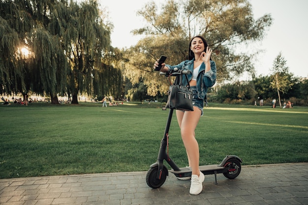街の通りに電動スクーターを持つ女性