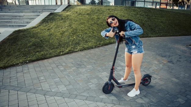 街の通りに電動スクーターを持つ女性