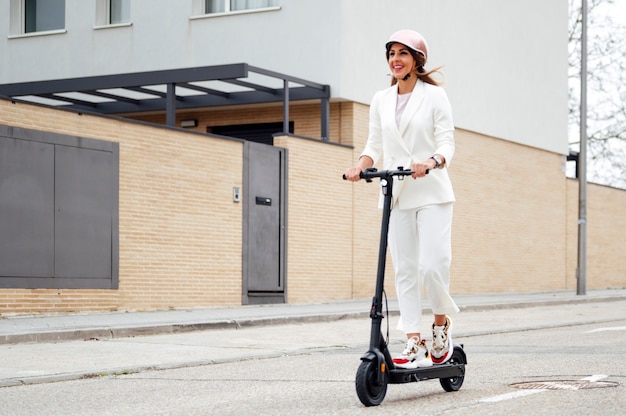 市内の電動スクーターとヘルメットを持つ女性