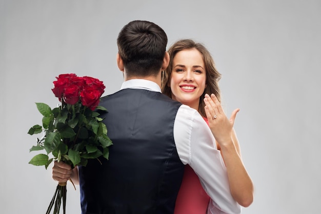 woman with engagement ring and roses hugging man