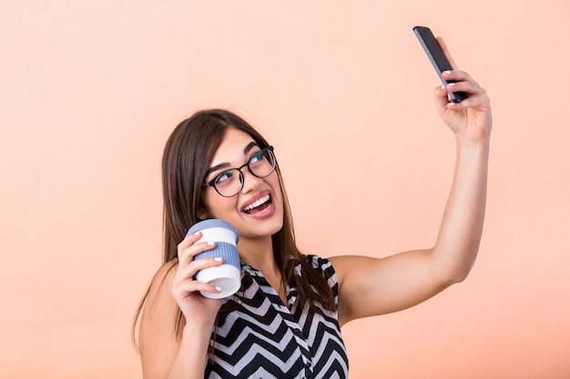 Donna con gli occhiali e la tazza di caffè in posa per selfie