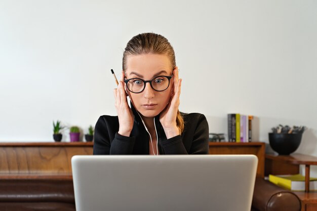 Woman with eyeglasses and headphones and laptop studying working online