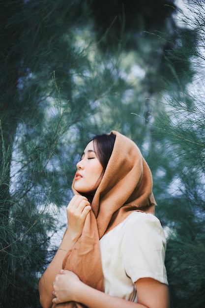 woman with eyes closed against trees