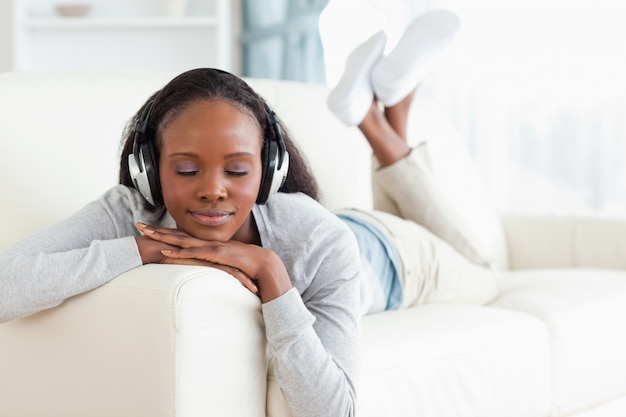 Donna con gli occhi chiusi godendo la musica sul suo divano