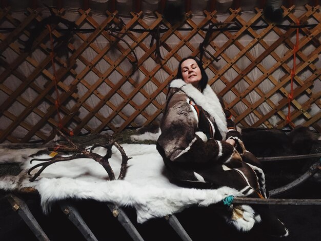 Foto donna con gli occhi chiusi seduta su una pelliccia