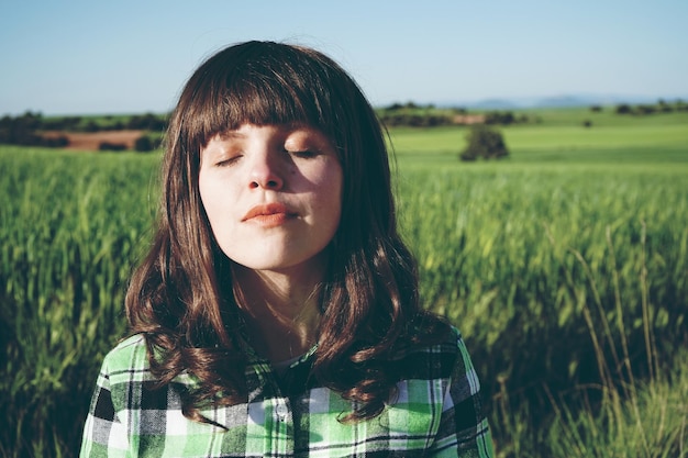 Woman with eyes closed standing on field during sunny day
