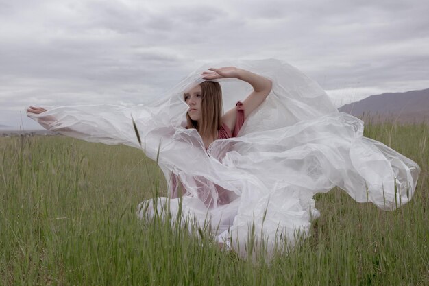 Photo woman with fabric standing at grassy field against cloudy sky