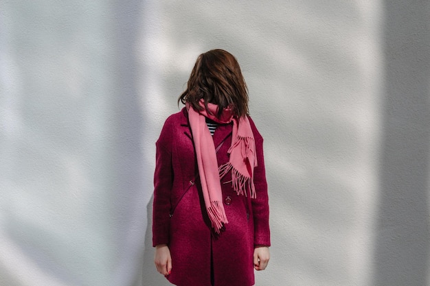 Photo woman with face hidden by hair standing against wall