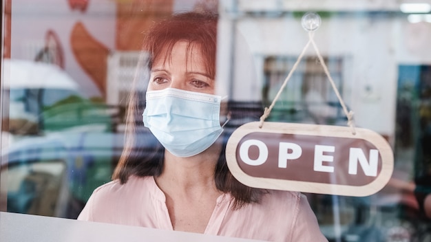 Foto donna con maschera facciale cambiando chiuso per aprire il segno sulla finestra che guarda fuori