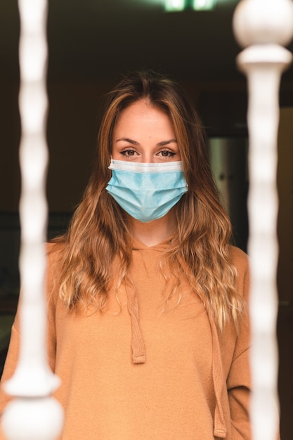 woman with face mask looking out the window