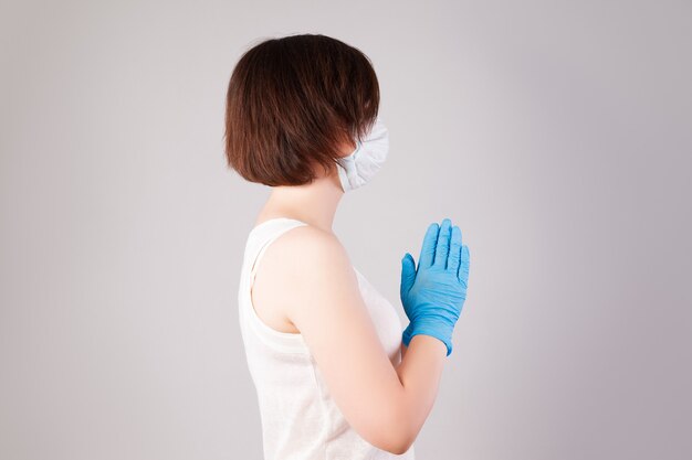 Woman with face mask and nitrile gloves on grey wall, outbreak of coronavirus disease 2019 or covid-19