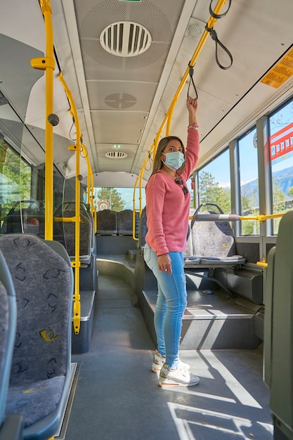 Donna con maschera facciale che viaggia in città sull'autobus