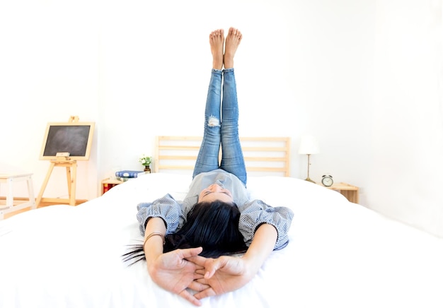 家でベッドに横たわっている足を上げた女性
