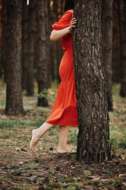 나무를 껴안고 소나무 숲에서 자연을 즐기는 고사리 문신을 한 여성