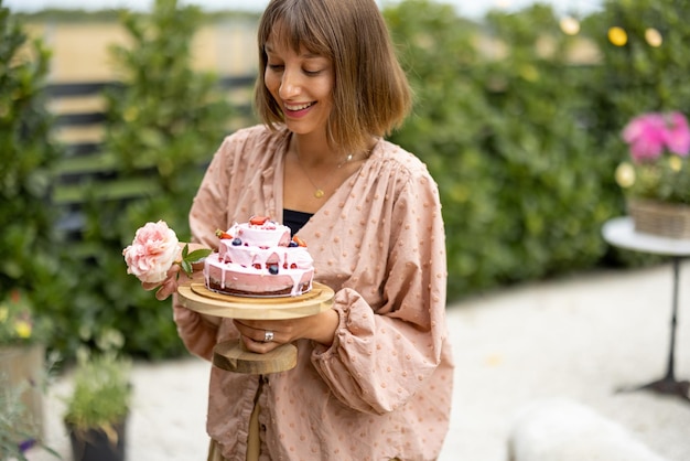 庭でお祝いケーキを持つ女性