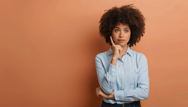 Photo a woman with a finger on her chin stands in front of an orange background