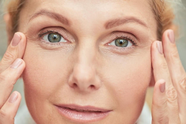 Woman with fingers near green eyes looking at camera