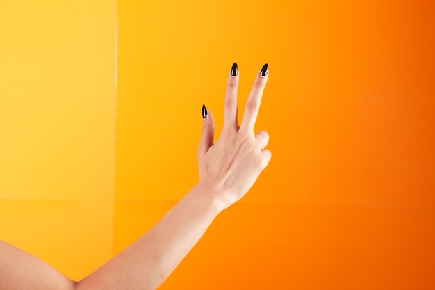 Woman with fingers shows three on orange background