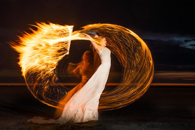 Foto donna con il fuoco sulla spiaggia