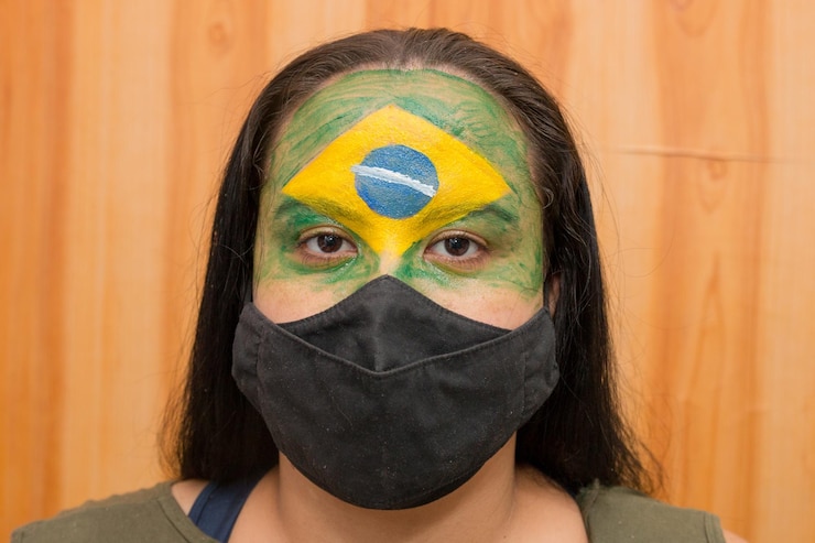 Photo 黒いマスクで彼女の顔に描かれたブラジルの旗を持つ女性
