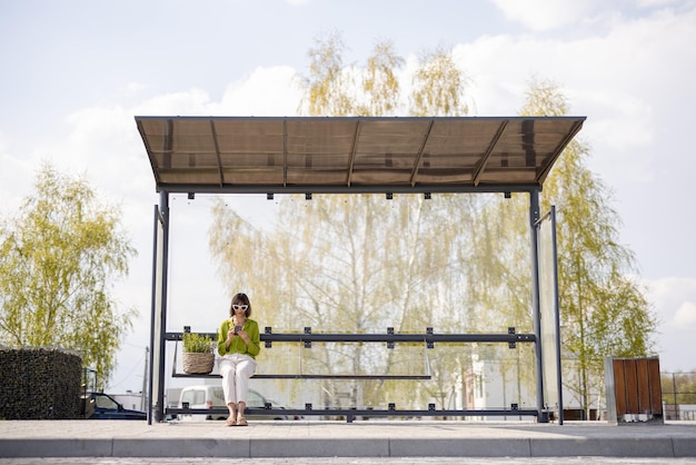 Woman with flowerpot at modern bus stop