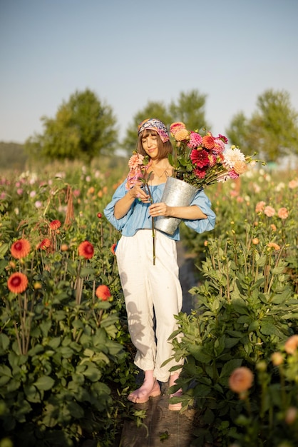 屋外のダリア農場で花を持つ女性