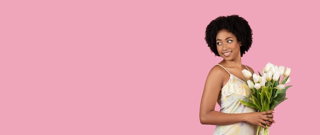 Woman with flowers looking away on a pink background