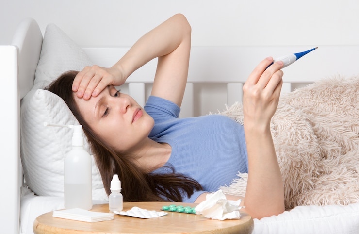Photo woman with flu virus, she's measuring her temperature with a thermometer.