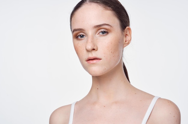 A woman with freckles and a white tank top