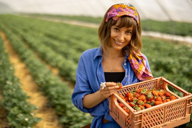 Woman with freshly picked up strawberries on farm