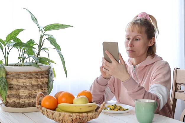 テーブルで果物とスマートフォンを持つ女性